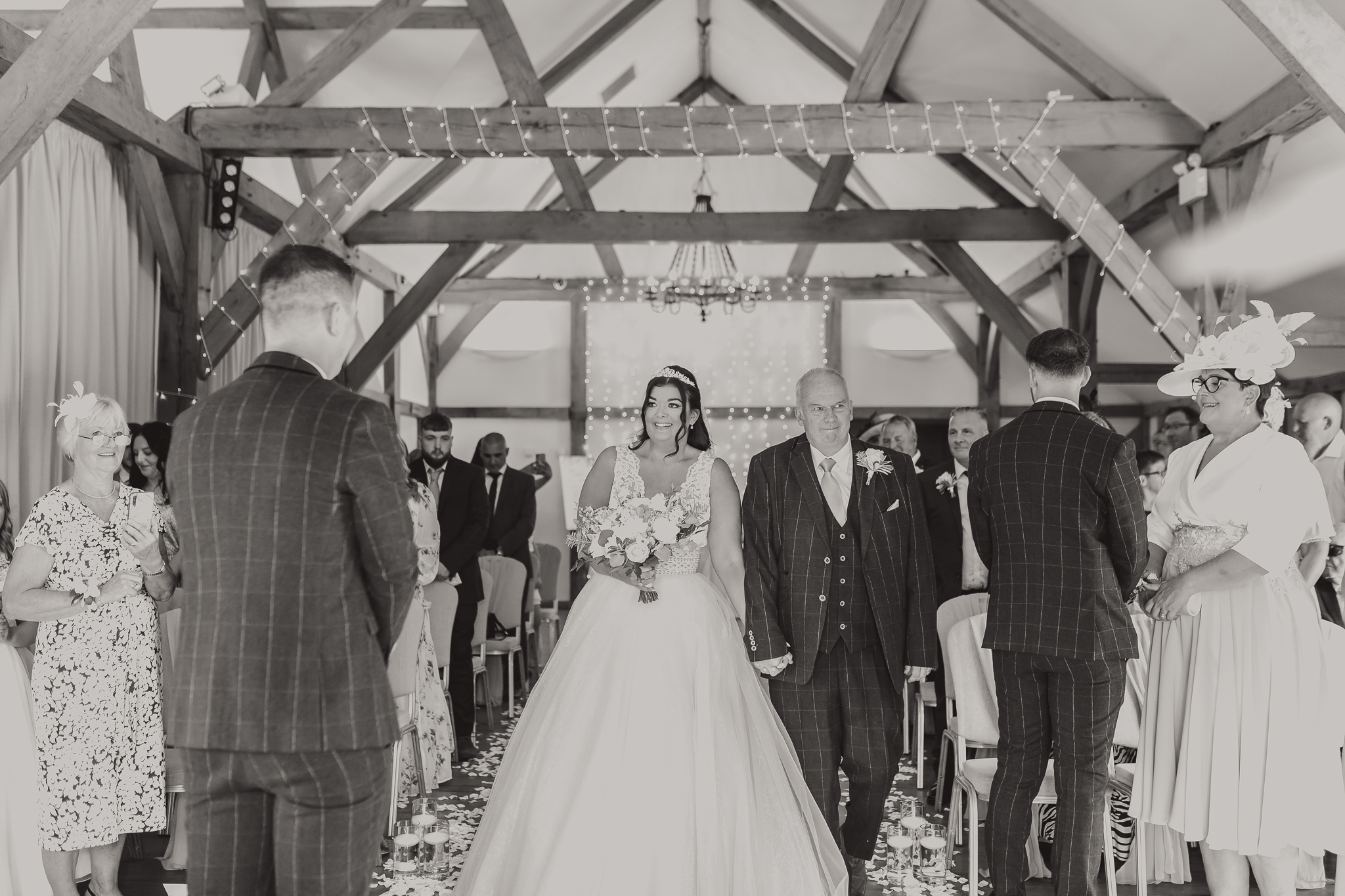 Aimee walking down the aisle at rustic wedding venue Sandhole Oak Wedding Barn, captured by Cheshire wedding photographer, Sophie Siddons