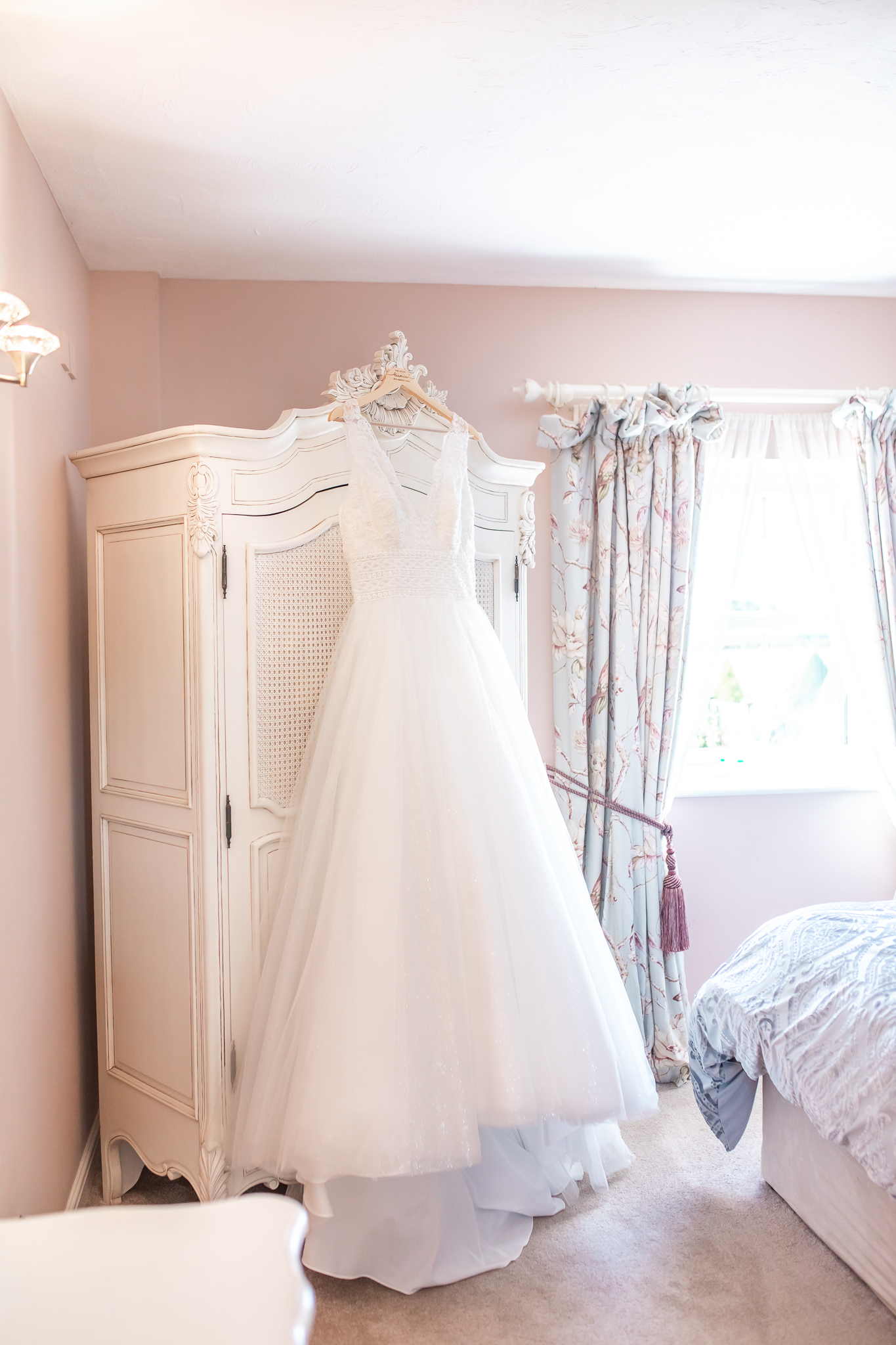 Wedding dress hanging from a white wardrobe at Sandhole Oak Barn in Cheshire