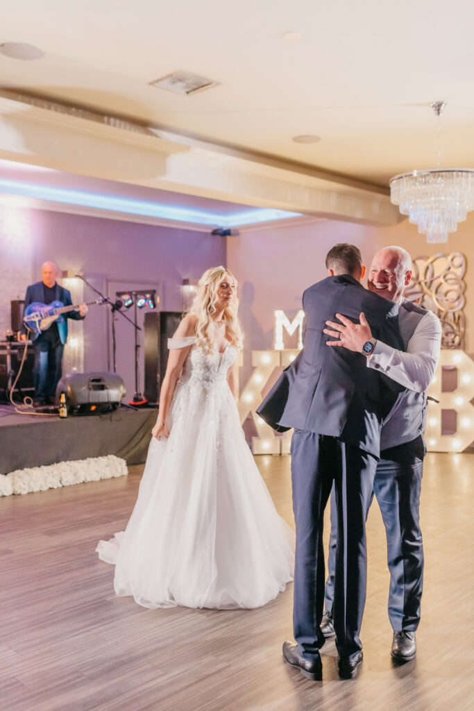 Groom and father-in-law hugging on the dance floor at Merrydale Manor Cheshire