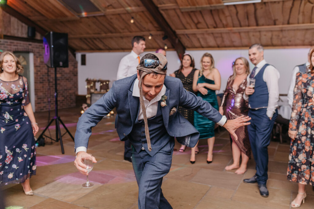 Groomsmen dancing with tie around head at Owen House Wedding Barn in Cheshire