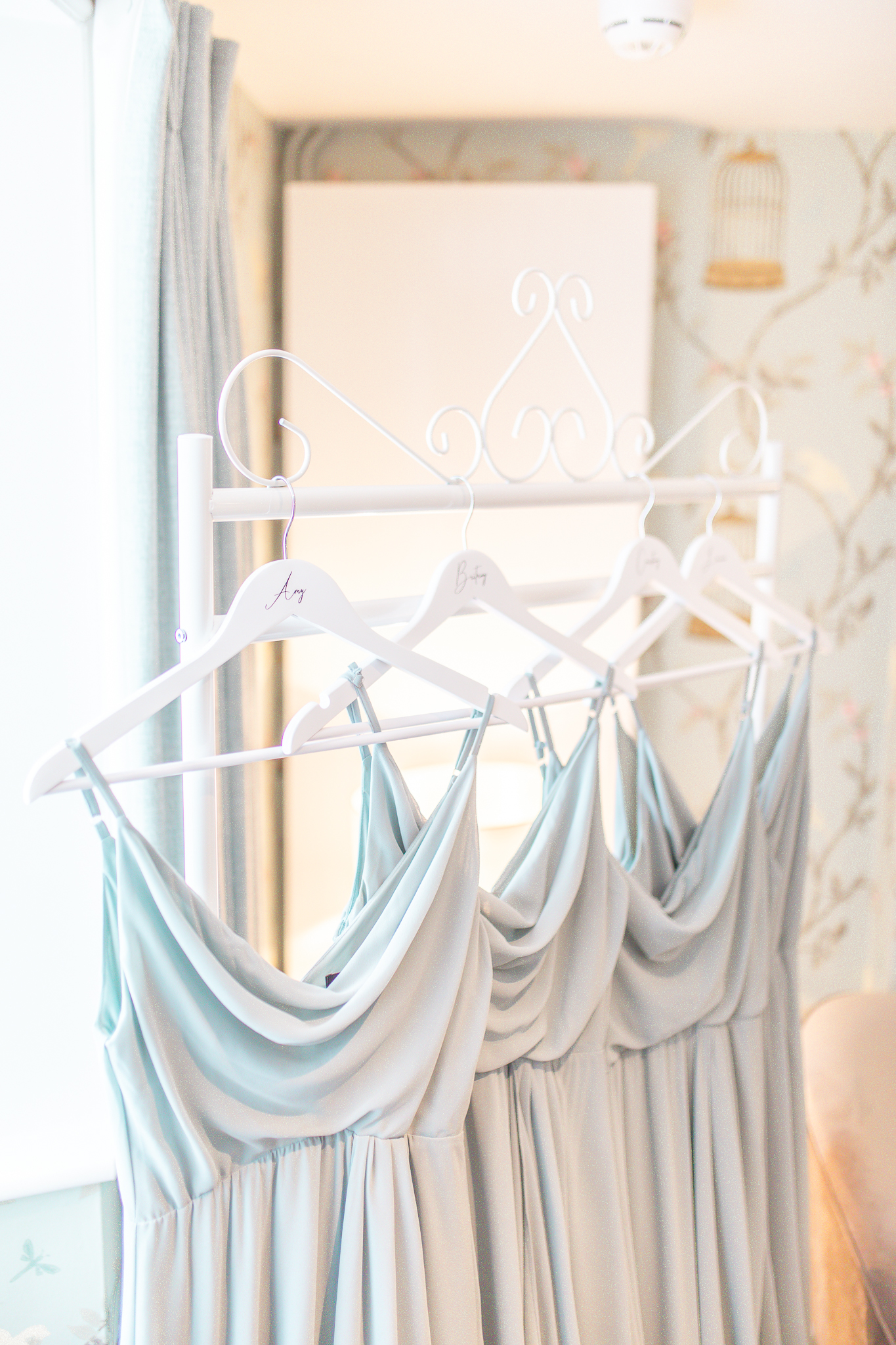 Close up of four light blue bridesmaid dresses hanging in Keepers Cottage at Combermere Abbey Cheshire wedding venue