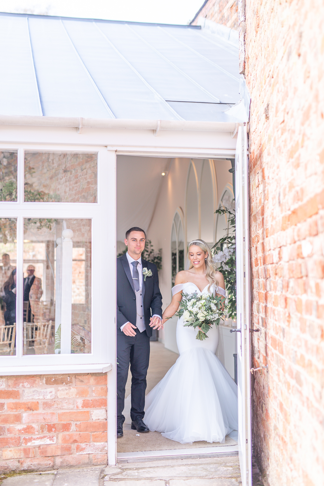 Spencer and Kelsey holding hands walking out of the ceremony room at Combermere Abbey