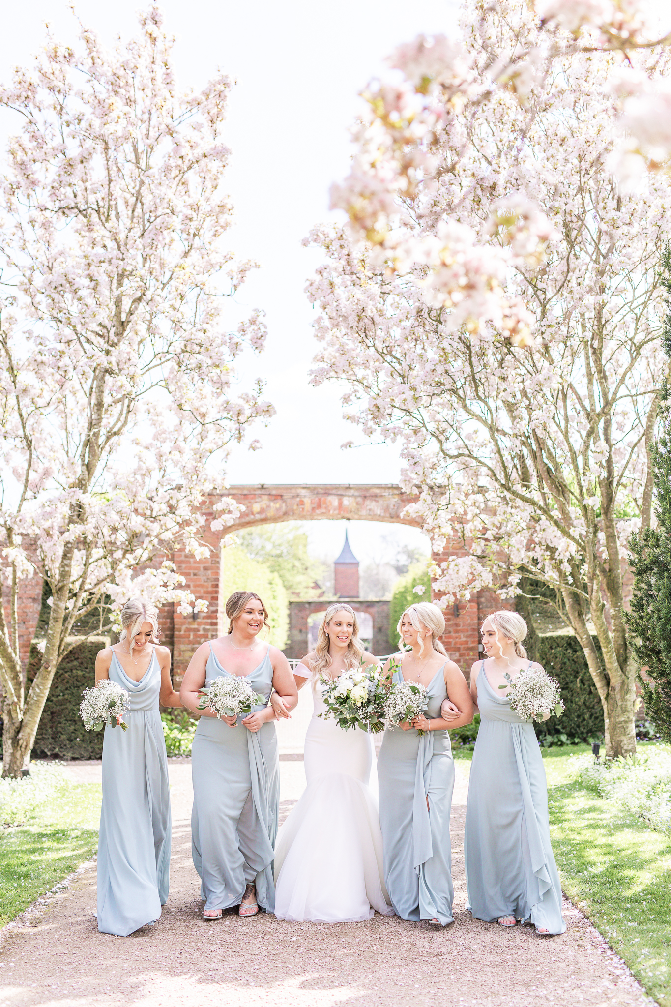 Kelsey and her bridesmaids walking in the grounds at Combermere Abbey in Cheshire, taken by wedding photographer Sophie Siddons