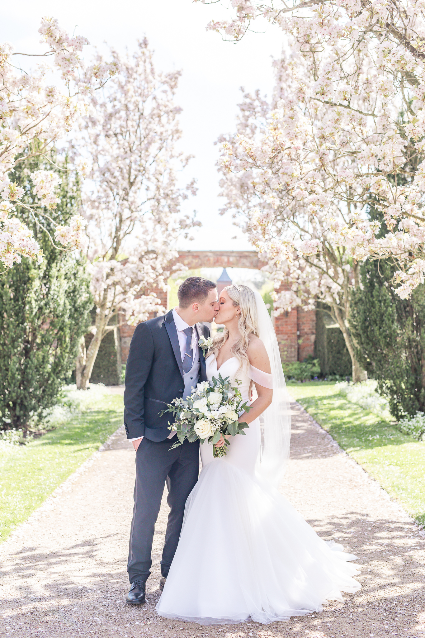 Bride and groom sharing a kiss in the gardens at Combermere Abbey