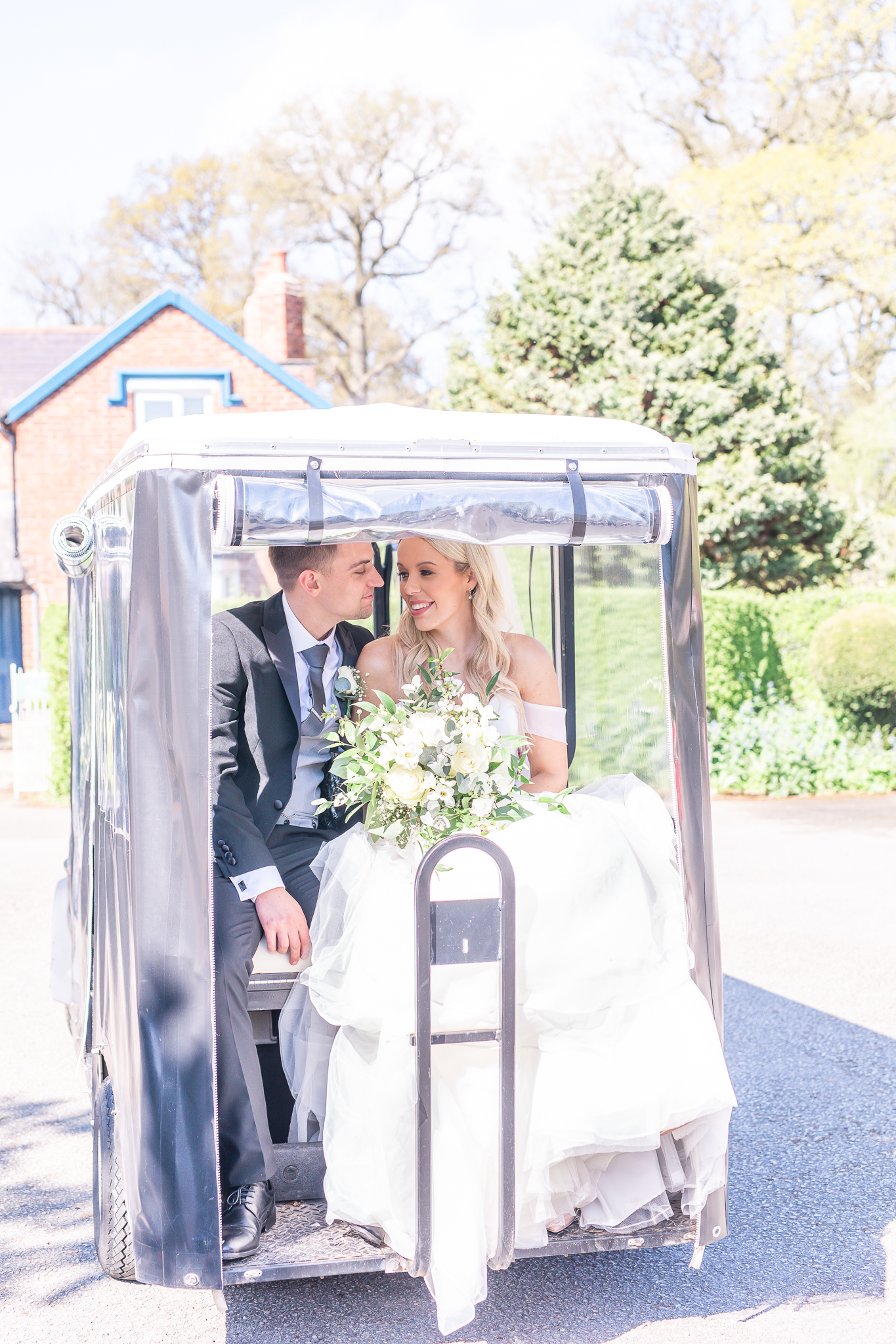 Bride and groom sharing a tender moment on a golf cart at Cheshire wedding venue