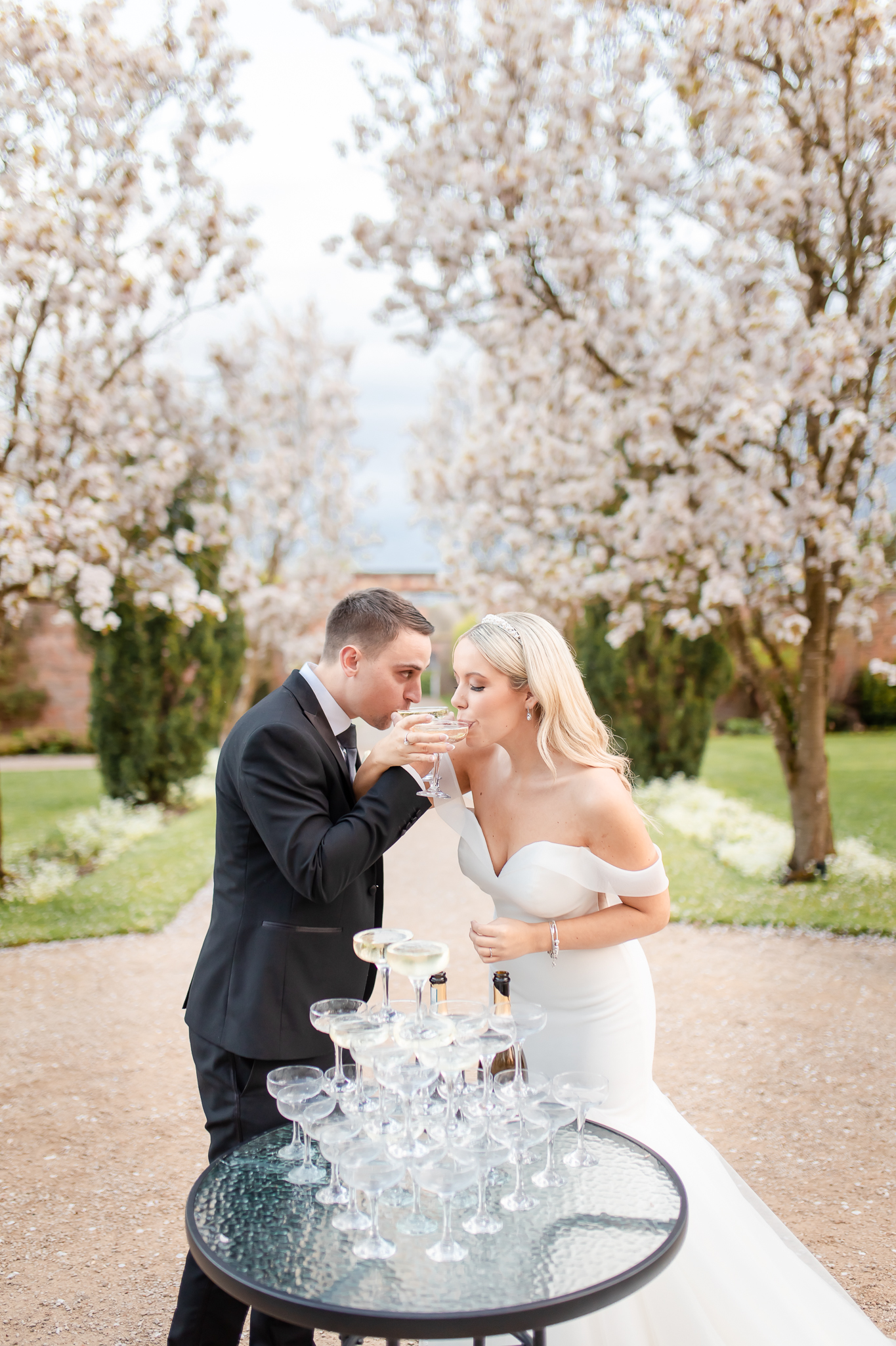 Bride and groom, Kelsey and Spencer drinking Champagne together in the gardens at Combermere Abbey