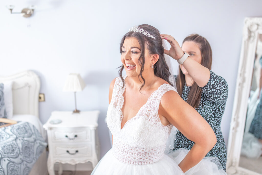 Bridesmaid laughing while putting in her veil in the bridal suit at Sandhole Oak Barn in Cheshire
