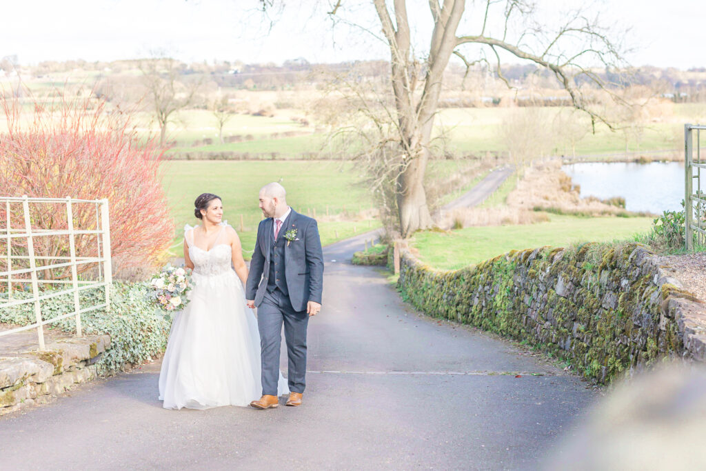 Abby and Jamie walking the driveway at The Ashes Wedding venue in Staffordshire, taken by North West wedding photographer, Sophie Siddons