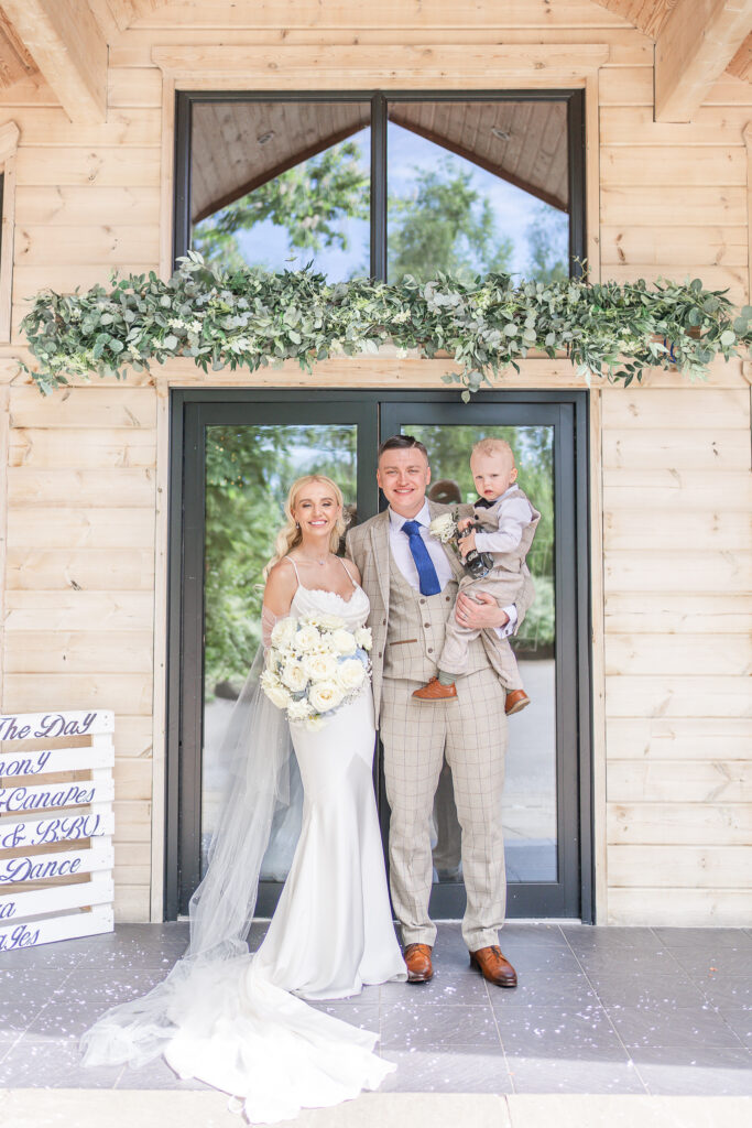 Bride, groom and their son standing outside Styal Lodge 
