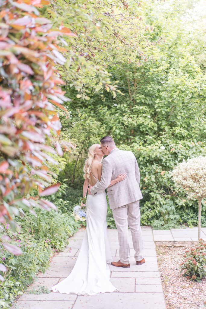 Bride and groom kissing in the gardens at Styal Lodge