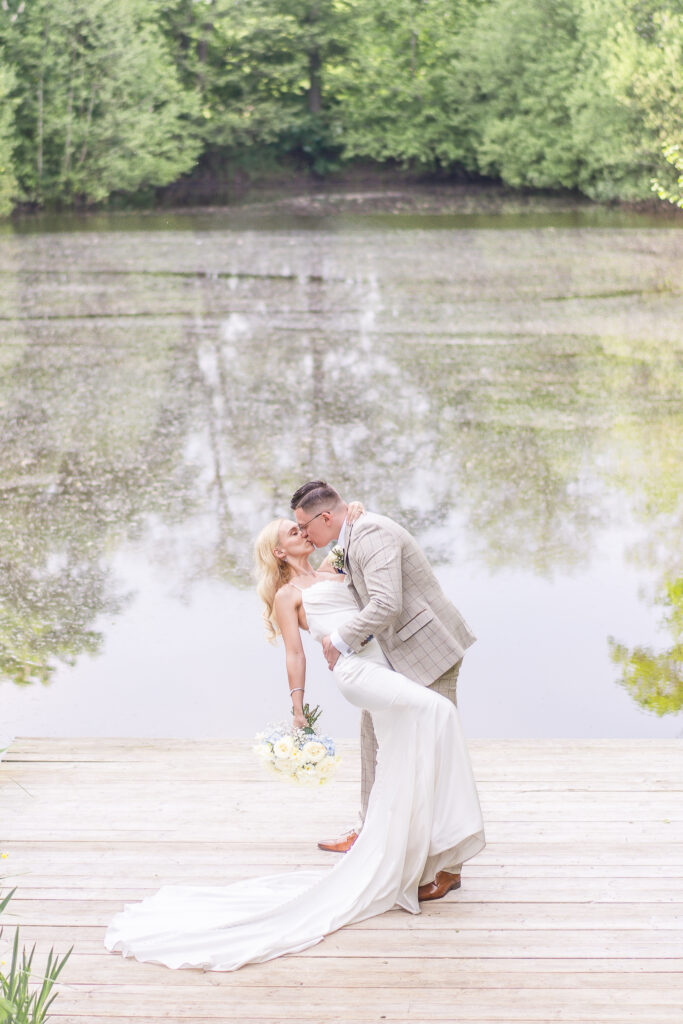 Bride and groom kissing in front of lake at Styal Lodge