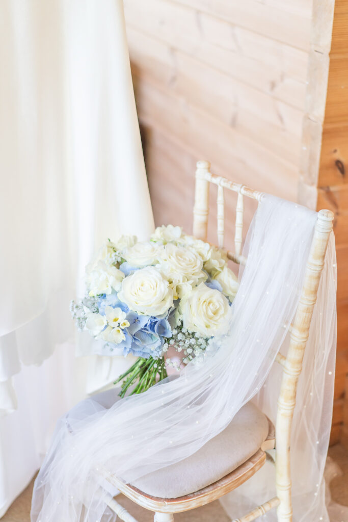 A bridal bouquet or white roses and blue hydrangeas