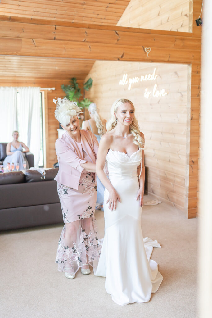 Mother of the bride helping bride into her dress